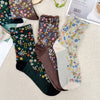 Three pairs of floral-patterned socks on a textured surface.