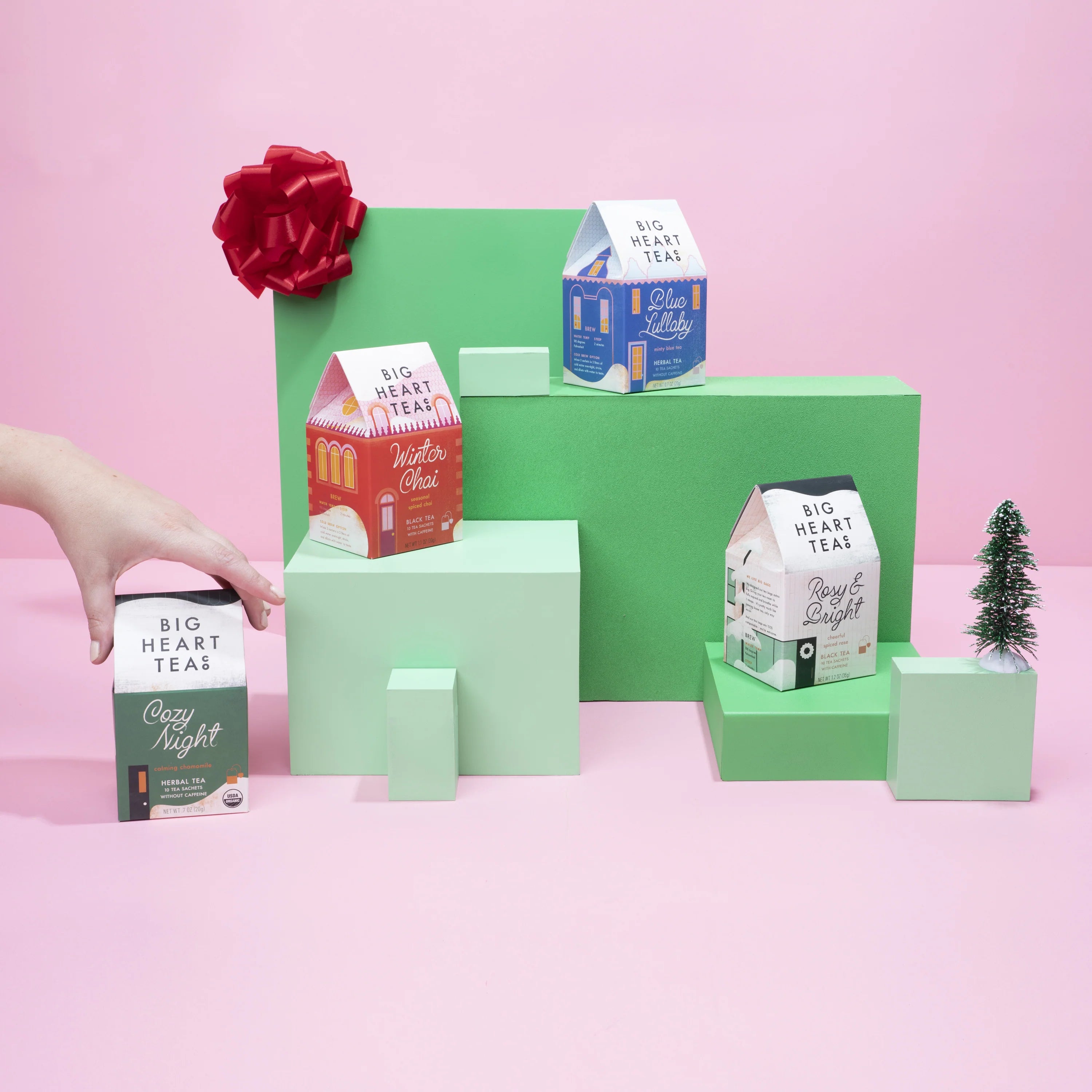 Collection of Big Heart Teas packaging on a pink background