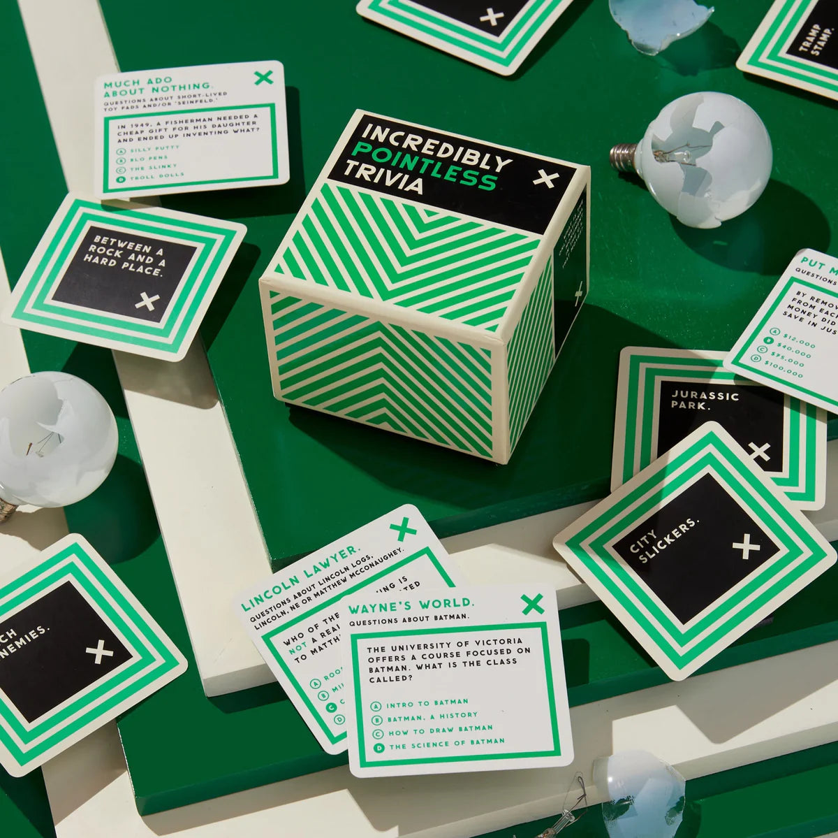 Green and white 'Incredibly Pointless Trivia' game box with cards on a green surface.
