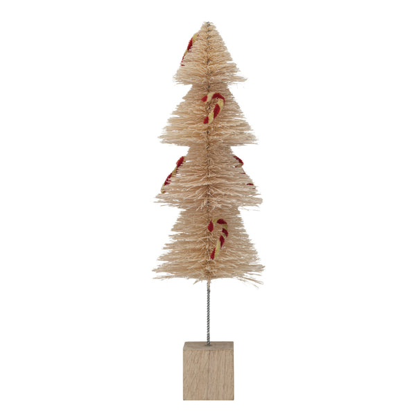A beige-colored sisal bottle brush tree with chenille candy cane decorations and a wooden base painted in white and red colors.