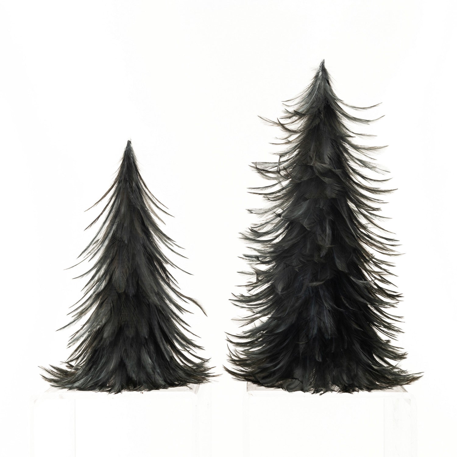 Two decorative feather trees with a Christmas tree shape, made of black feathers, displayed on a white background.