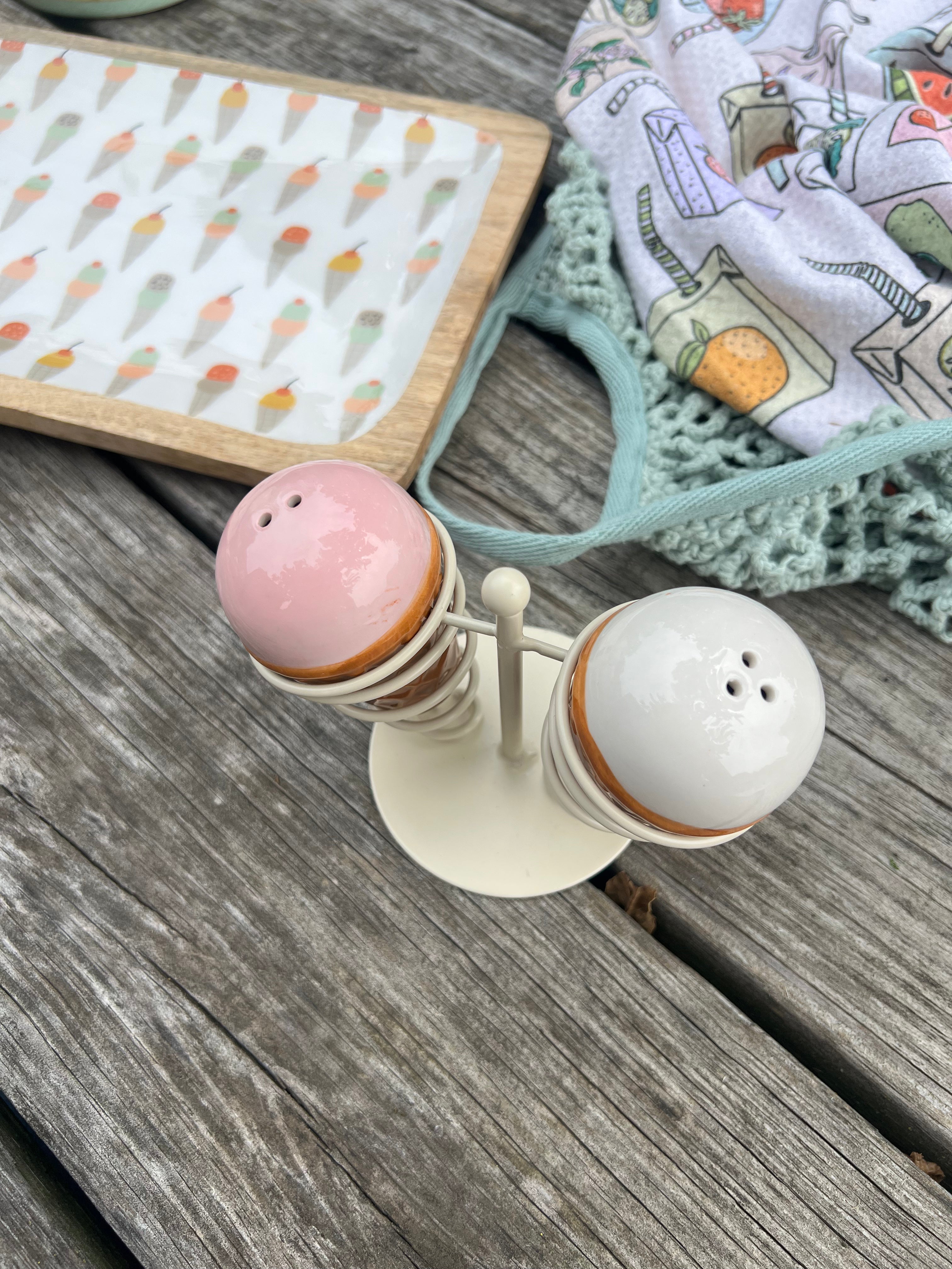 Salt and pepper shakers on a wooden surface with a patterned cloth in the background