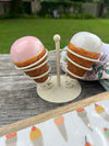 Decorative stand with spherical ceramic items on a wooden surface outdoors.