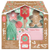 A gingerbread baking set packaging with various baking tools and ingredients like cookie cutters, a spatula, measuring spoons, and recipe cards, designed for children.