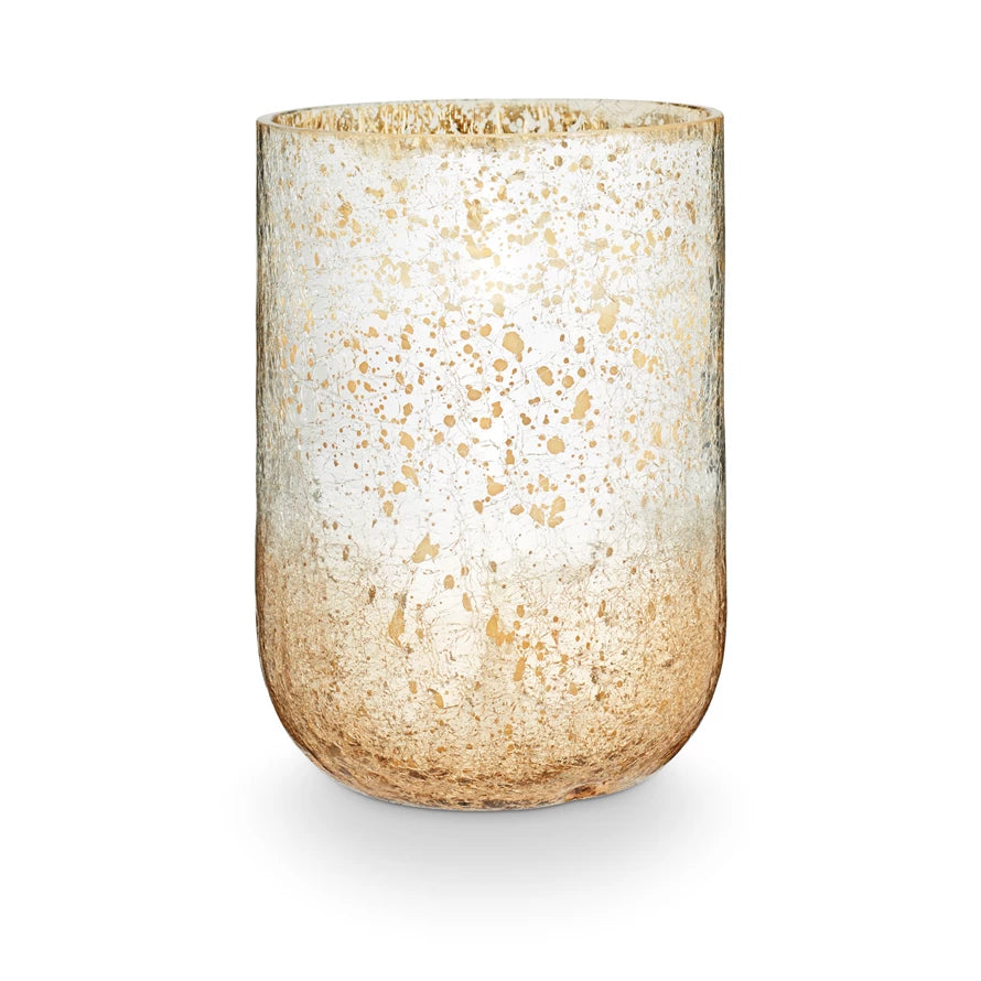 A large radiant glass candle with a two-tone metallic finish, predominantly in shades of beige and white.