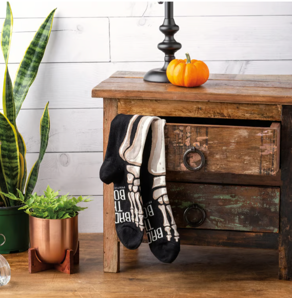 Pair of black and white socks hanging on a wooden drawer with decorative items.