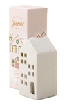 A beige ceramic incense cone holder shaped like a house, with 'Holiday Town' and 'Incense House' text on the top, next to its pink packaging box decorated with Christmas motifs.