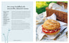 Sandwich with mozzarella, salami, and tomato on a picnic setting with a basket and cutlery.
