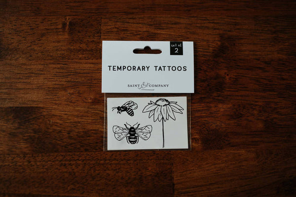 A pack of temporary tattoos featuring a coneflower and honeybees, placed on a wooden surface.