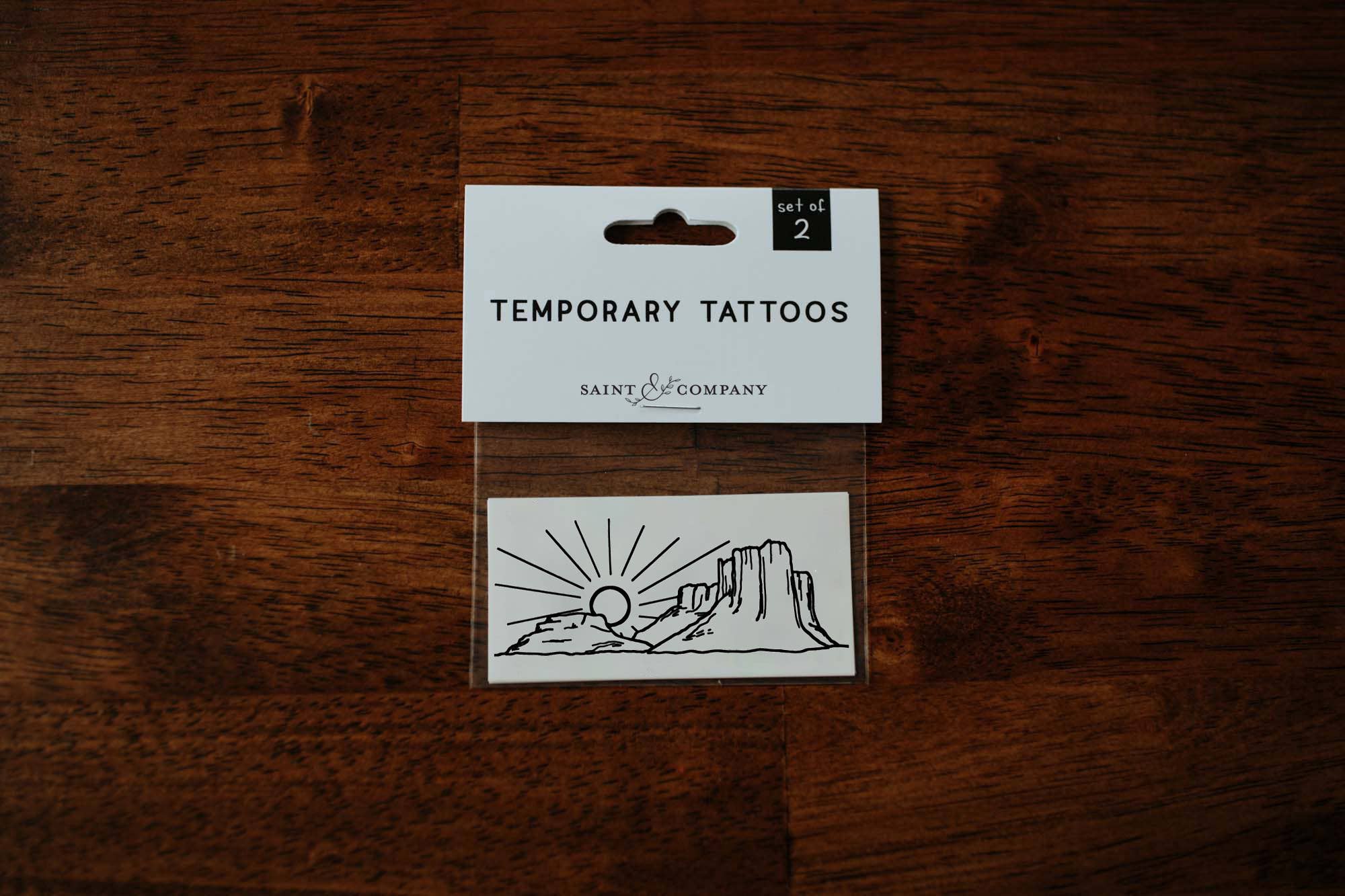 A set of temporary tattoos featuring a hand-drawn desert scene, packaged on a card.