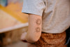 A person is showing off a temporary tattoo of two sun designs on their forearm.