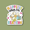 Sticker with a cartoon flower holding a book and text 'Happiest when I'm Reading' on a green background