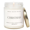 A clear jar soy candle with a label reading 'Christmas' for the festive season, indicating a fresh cut trees, orange & cloves scent, and being made in the USA.