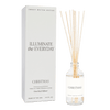 A clear reed diffuser with Christmas-themed fragrance notes, including apple cider, cinnamon, fresh cut Christmas tree, cookies, orange peels, and cloves. The product packaging is also visible with the text 'Illuminate the Everyday' and 'Christmas'.