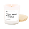 An 11 oz soy wax candle with a label reading 'Fresh Apple Blossom' from Sweet Water Decor, placed in a white jar with a cotton wick.