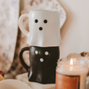White and black mug with polka dot design on a surface with a blurred background