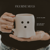 Person holding a white mug with black dots, labeled as a figurine mug with product details.