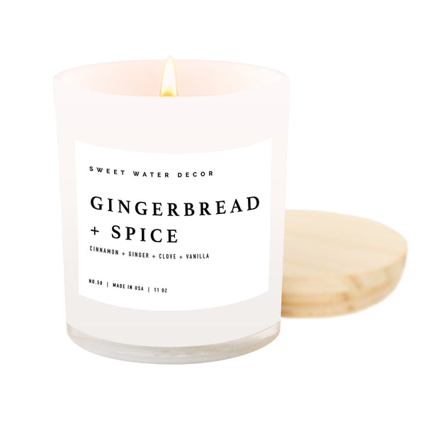 An 11 oz soy candle with a white label that reads 'Gingerbread + Spice' along with the scents listed. The candle is in a clear jar with a wooden lid.