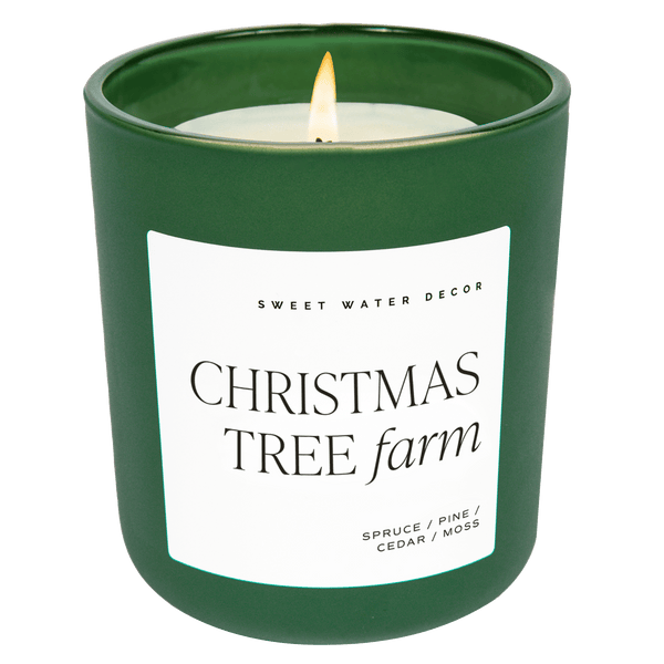 A green matte glass jar with a label that reads 'Christmas Tree Farm' and a brief description of the scents including pine, spruce, and cedarwood.
