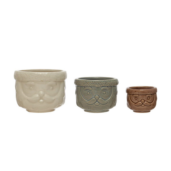 A set of three ceramic decorative containers with a Santa Claus design, in different sizes, with a beige, gray, and brown color scheme.