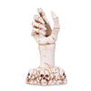 A beige candle holder in the shape of a hand with a skeleton design and a skull at the base.