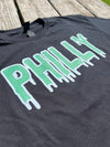 Black t-shirt with 'PHILLY' printed in green on a wooden surface