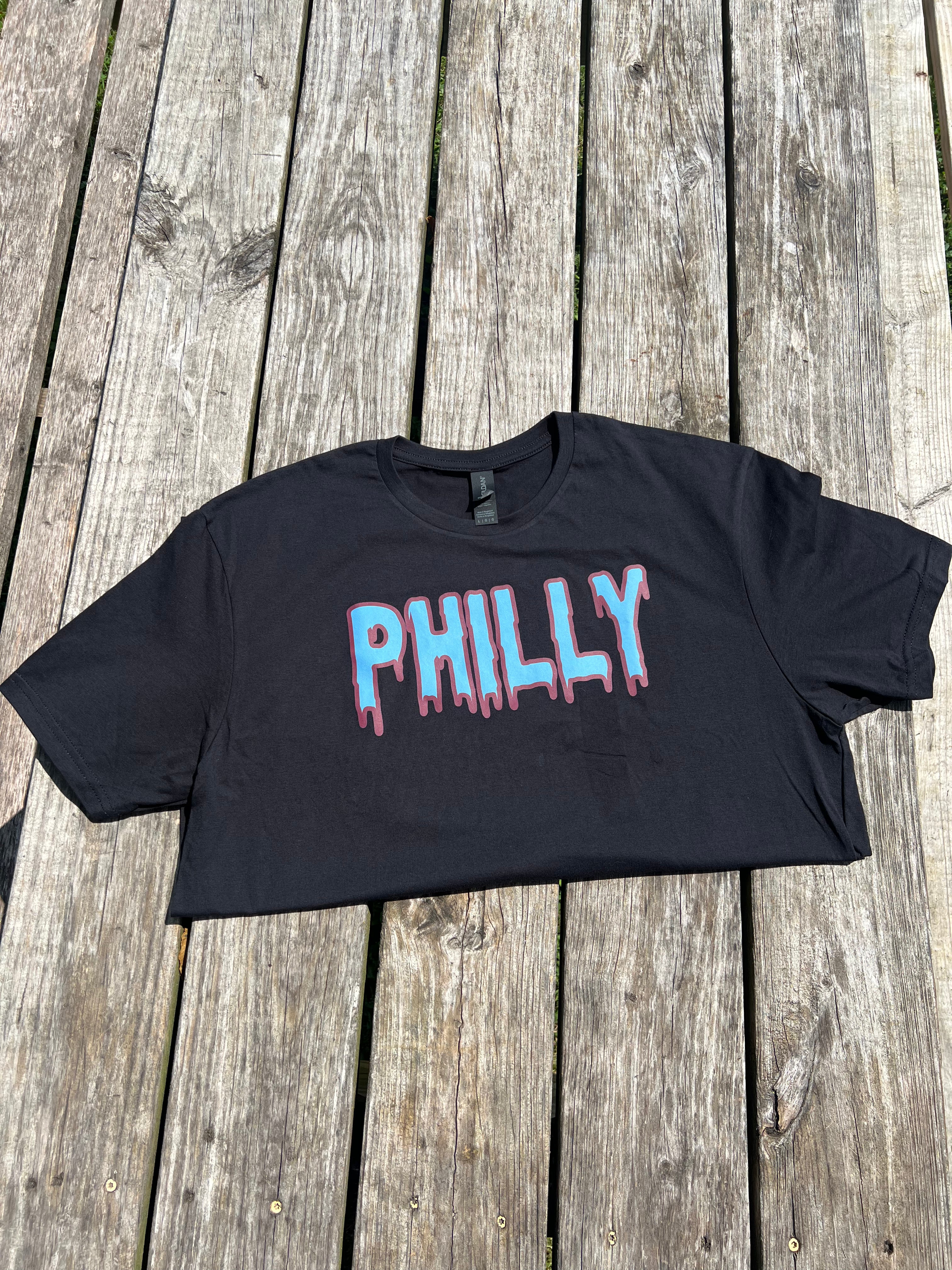 Black crop top with 'PHILLY' printed on it, placed on a wooden surface.