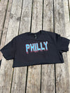 Black crop top with 'PHILLY' printed on it, placed on a wooden surface.