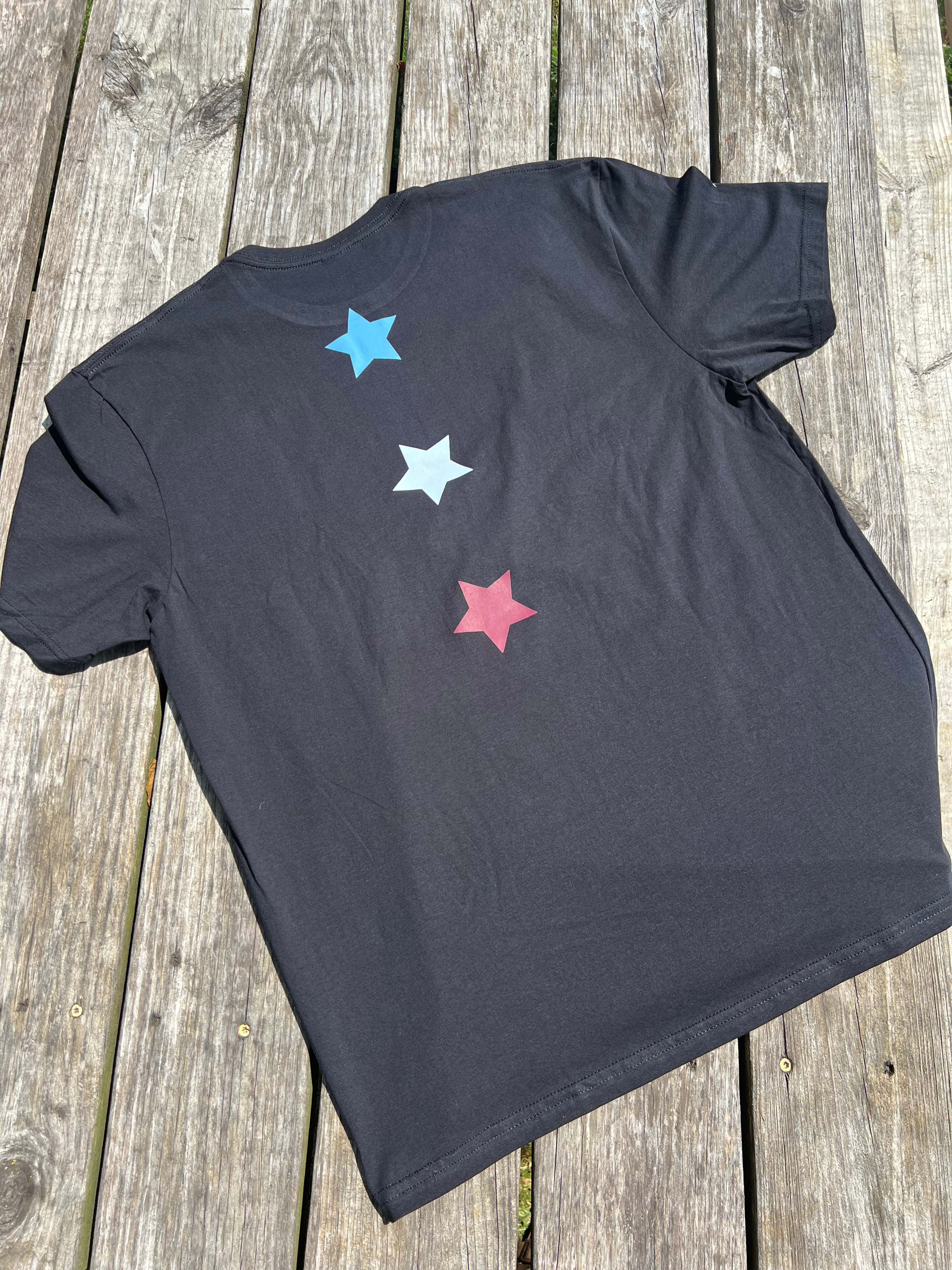 Black t-shirt with colorful stars on a wooden surface