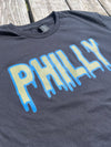 Black t-shirt with 'PHILLY' printed in blue and light green on a wooden surface
