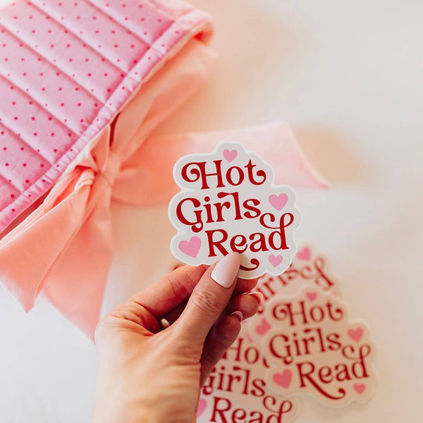 Hand holding a 'Hot Girls Read' sticker with a pink background