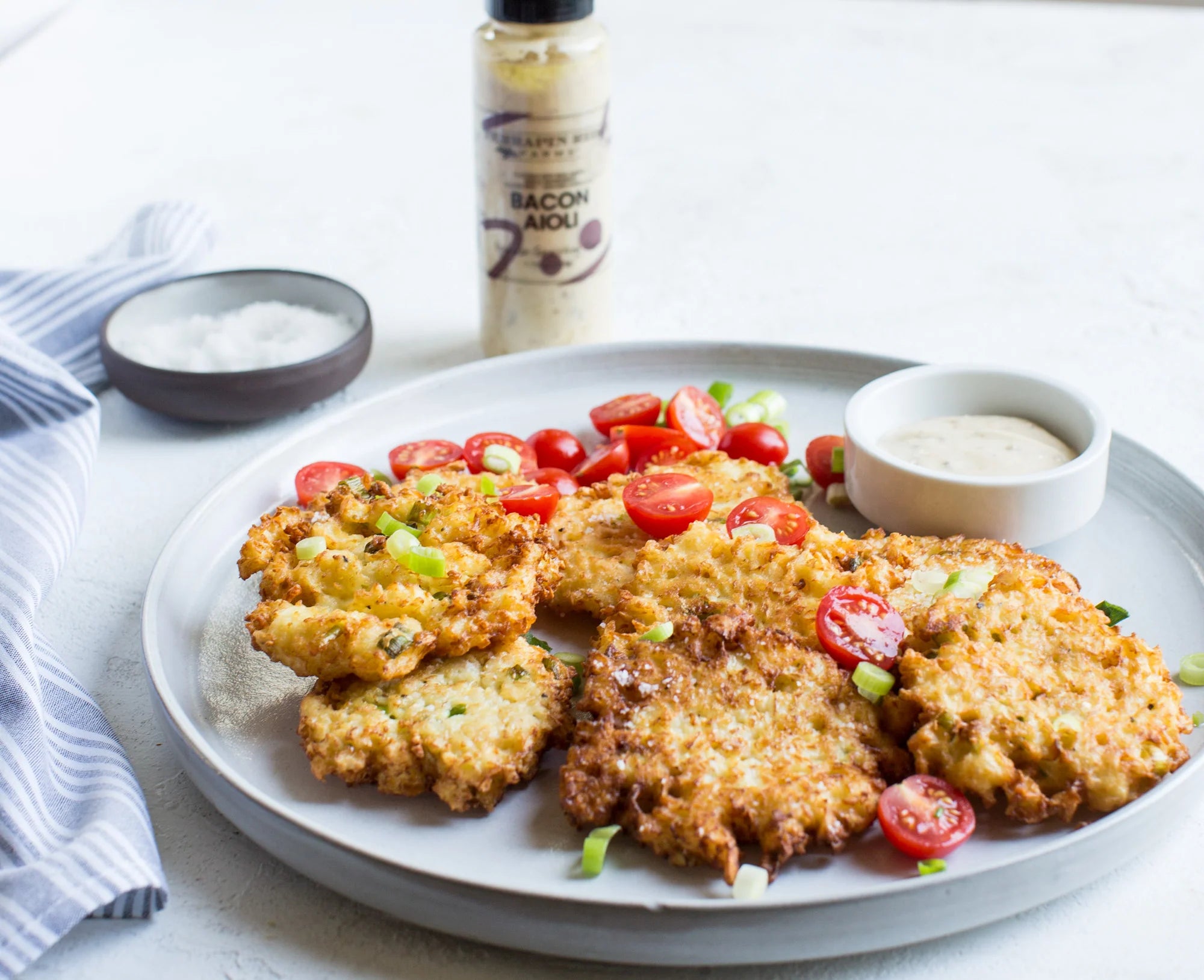 Fried chicken cutlets on a plate with tomatoes and a bottle of bacon sauce in the background.