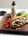 Submarine sandwich with bacon aioli on a wooden cutting board with tomatoes and lettuce.