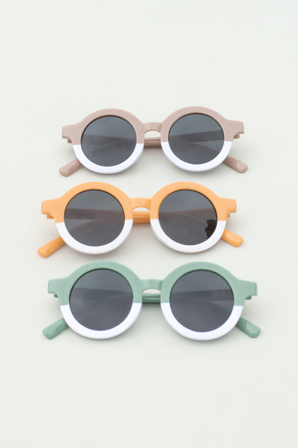 A collection of toddler round sunglasses in three colors: pink, orange, and green, each with white frames and dark lenses.