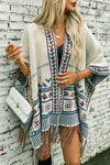 Woman wearing a patterned poncho with a white brick wall background
