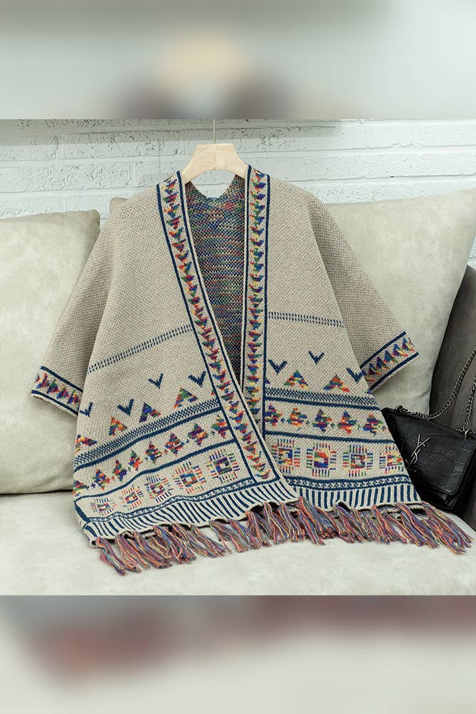 Beige patterned shawl with colorful designs on a hanger against a neutral background