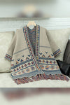 Beige patterned shawl with colorful designs on a hanger against a neutral background