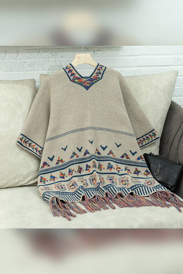 Beige embroidered dress with colorful patterns on a hanger against a neutral background