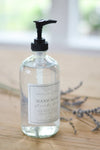 Clear hand soap bottle with black pump on a wooden surface with blurred background