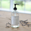 Hand soap bottle with pump on a wooden surface with lavender flowers.