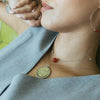 Person wearing a necklace with a coin pendant and red bead