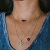 Close-up of a person wearing two gold necklaces with beads and a pendant.