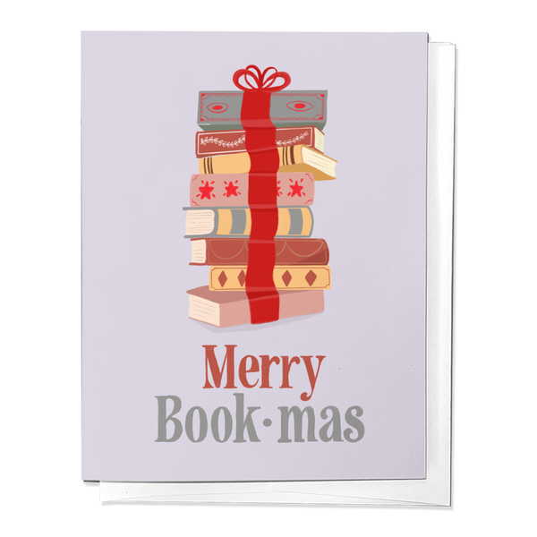 A greeting card with a stack of books wrapped with a red bow and the text 'Merry Book-mas' printed on the front. The card is displayed against a white background.