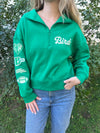 quarter zip sweatshirt featuring a sleeve of patches on a model standing outside