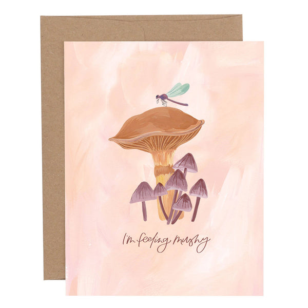 A greeting card with an illustration of mushrooms and a dragonfly, and the phrase 'I'm feeling mushy' written on it.