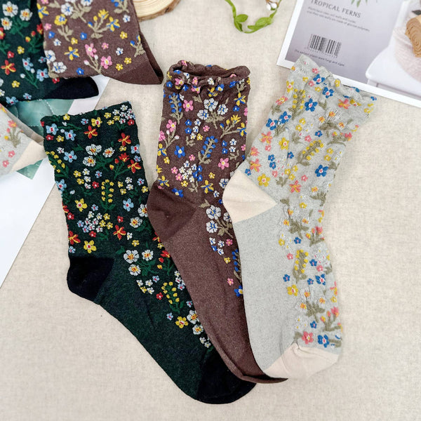 Three pairs of floral-patterned socks on a textured surface.