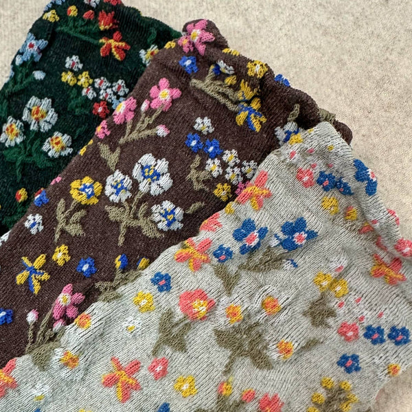 Embroidered socks with floral patterns in various colors on a textured surface.
