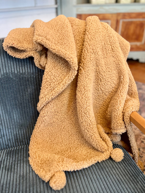 Beige sherpa blanket draped over a gray chair