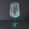 A clear glass goblet with a distinct turquoise-blue tint at the rim and base, set against a dark gray background.