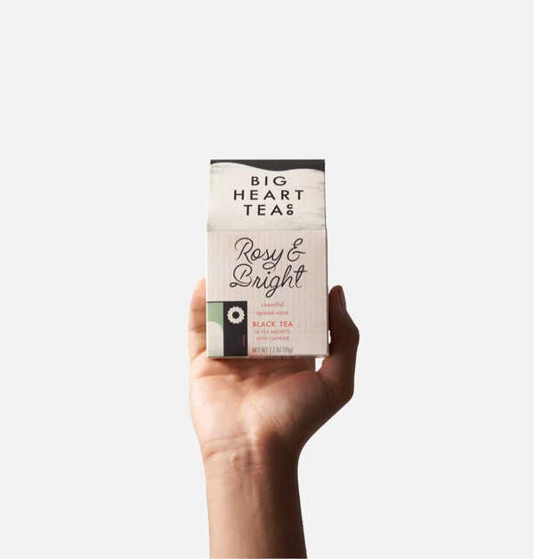 Hand holding a box of Big Heart Teas Rosy & Bright tea against a white background